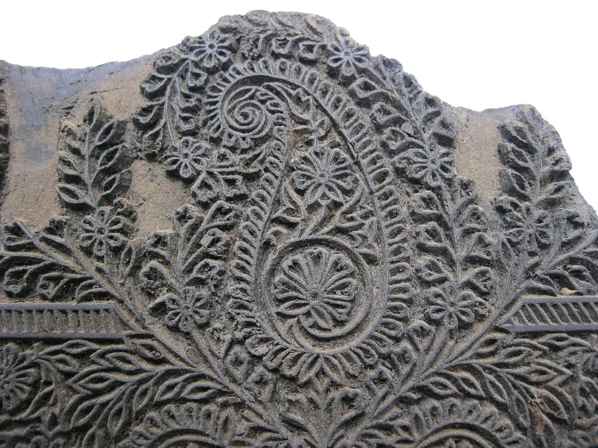 A hand-carved wooden textile printing block with a paisley and floral design.