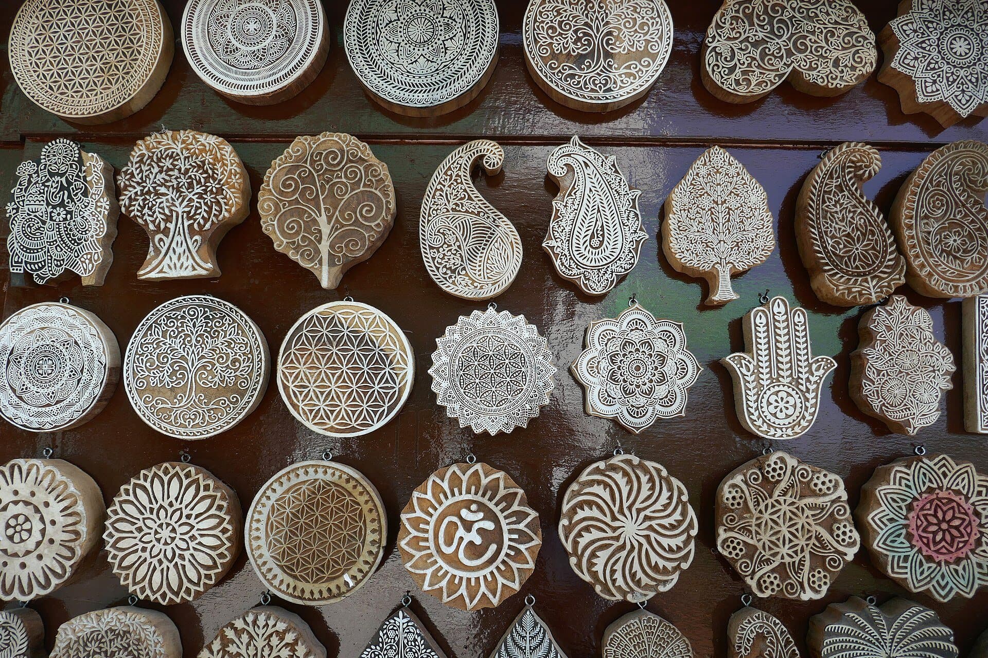 Rows of hand-carved wooden textile printing blocks with floral and paisley designs.